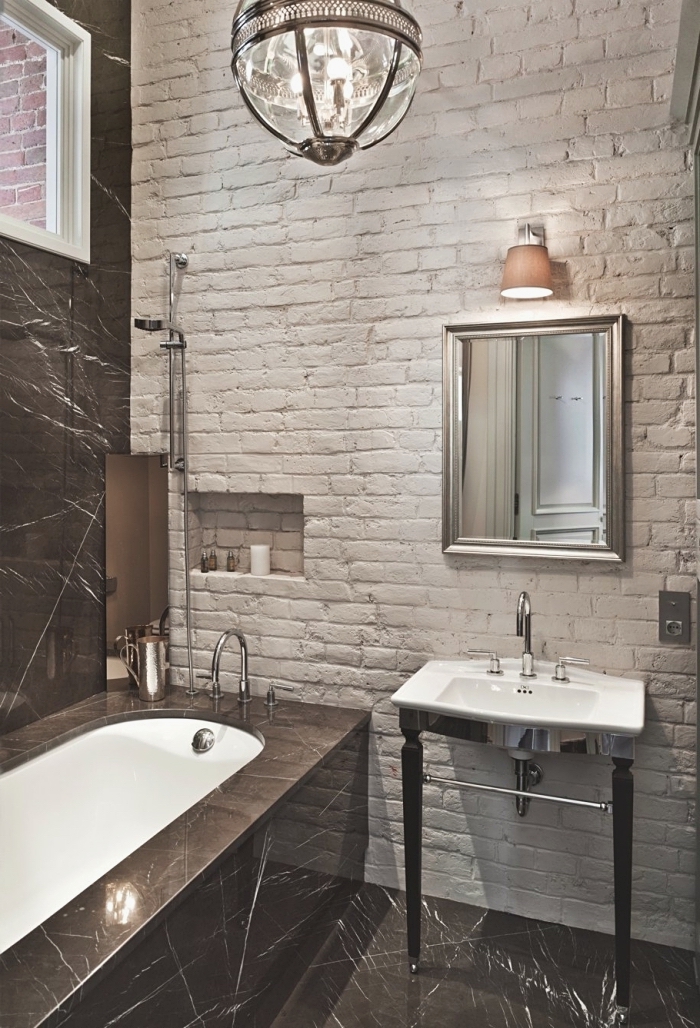déco moderne salle de bain avec baignoire aux murs en briques blanches et carrelage noir avec baignoire et lavabo en blanc
