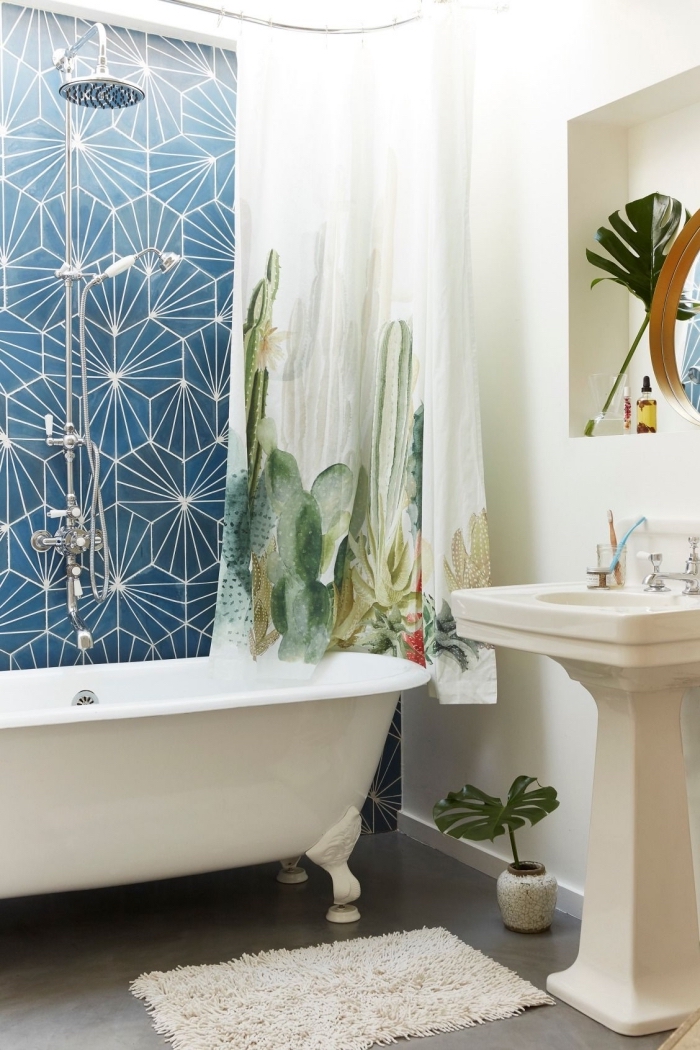 déco motifs tropicaux larges dans une petite salle de bain moderne aux murs blancs et sol imitation béton avec rideaux baignoire plantes