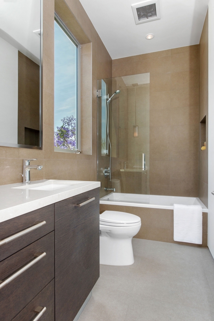 modèle petite salle de bain avec baignoire aux murs beige et plancher gris avec plafond blanc, meuble lavabo à comptoir blanc et portes foncées