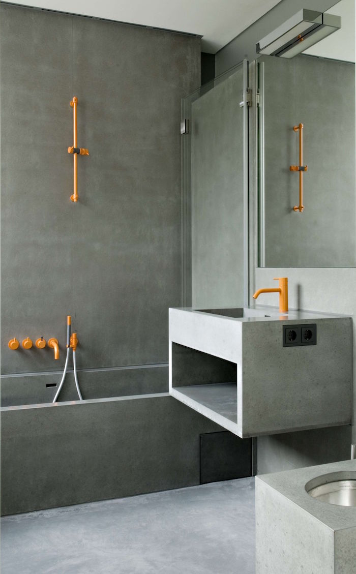 douche à l'italienne beton ciré sur mur salle de bain moderne et design avec lavabo en ciment et plomberie metal orange