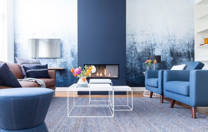 deco salon bleu et blanc associant harmonieusement les couleurs froides, la cheminée peinte en bleu marine assortie au papier peint imprimé graphique du mur attenant