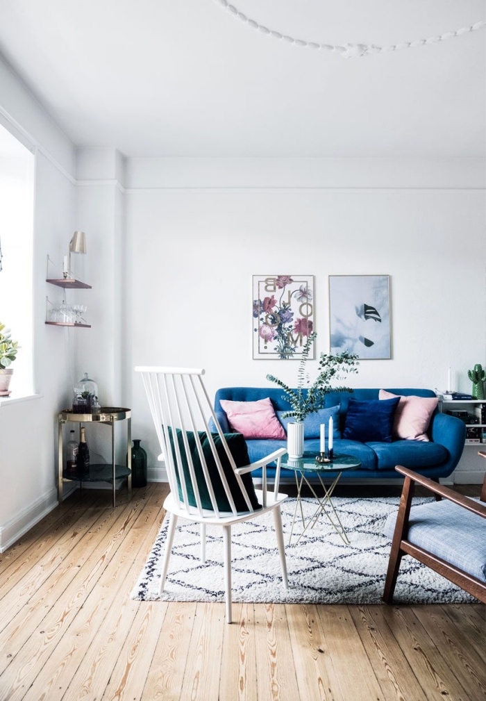 salon blanc scandinave avec un canapé bleu roi sublimé par des coussins rose et bleu indigo