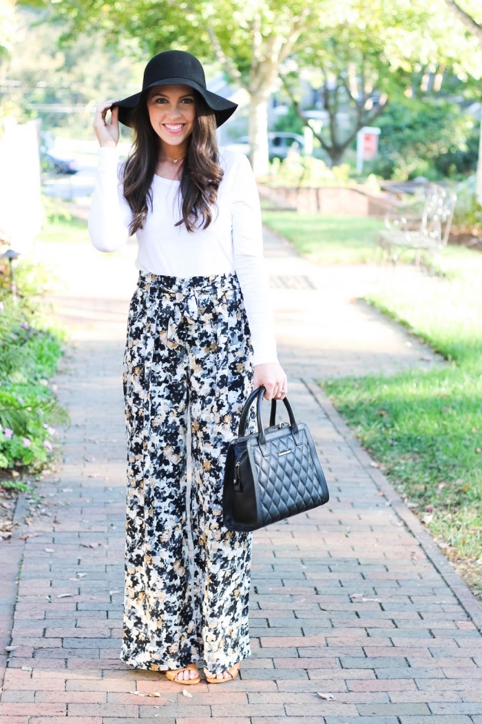 vision chic femme en pantalon taille haute à design fleuri avec blouse blanche et accessoires noirs sac à main et capeline