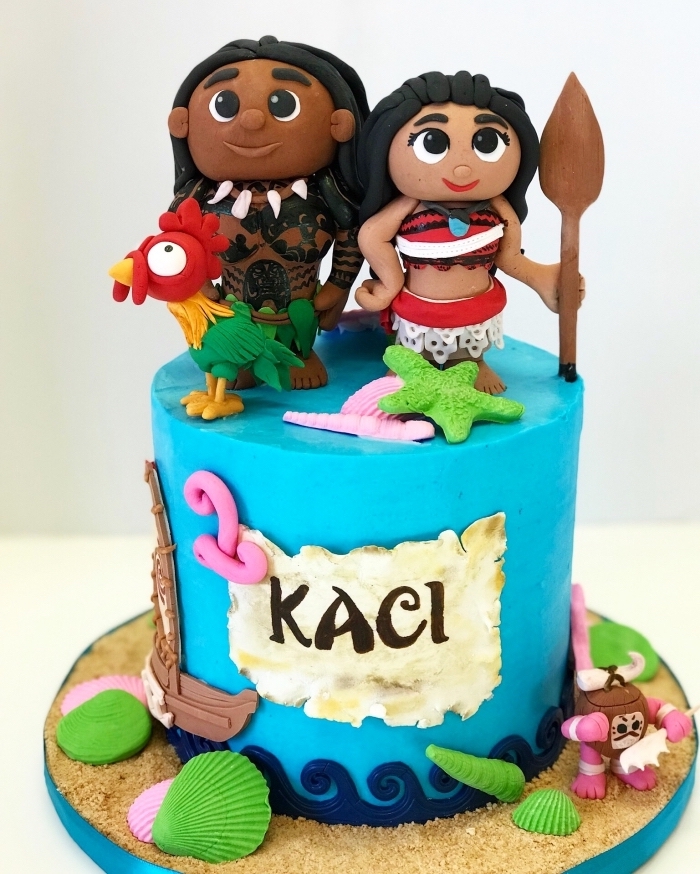 modèle de deco vaiana sur un gâteau DIY au glaçage bleu turquoise avec figurines des personnages Vaiana et Maui