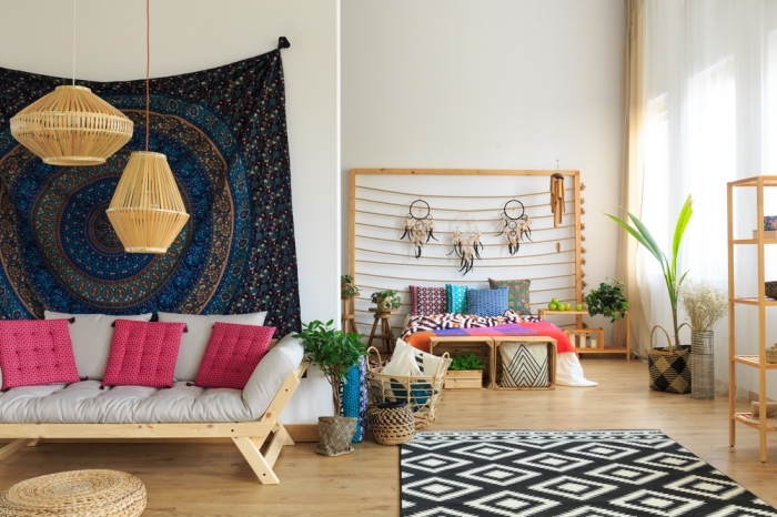 déco logement étudiant à design chic et boheme, salon aménagé avec meubles de bois avec canapé couvert de coussins roses et tapisserie murale foncée