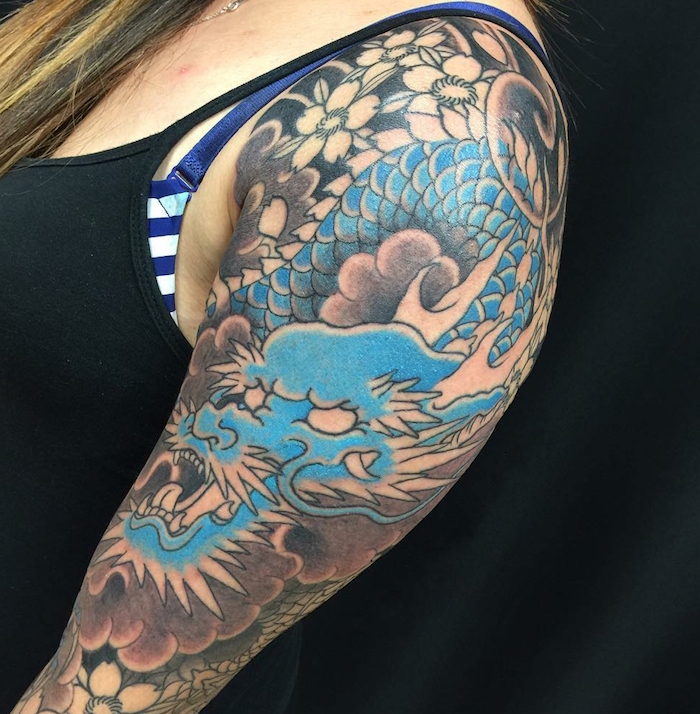 tatouage haut du bras et epaule femme style tatouage japonais irezumi dragon fleurs cerisier noir et bleu turquoise