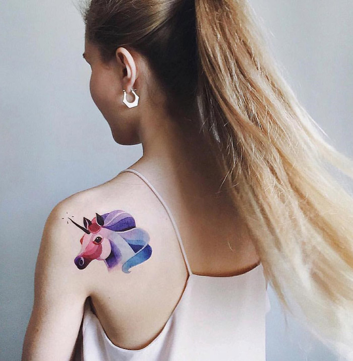 photo de tatouage de licorne en couleurs aquarelle rose bleu violet sur épaule de femme