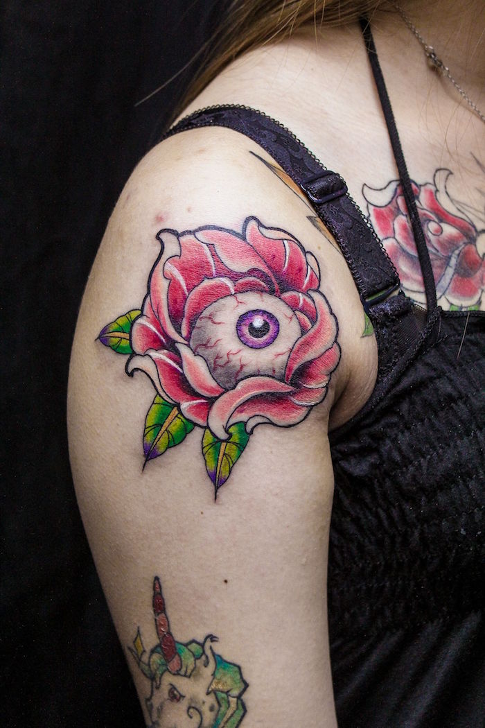 tattoo haut du bras femme fleurs de lotus avec oeil rose et vert sur épaule
