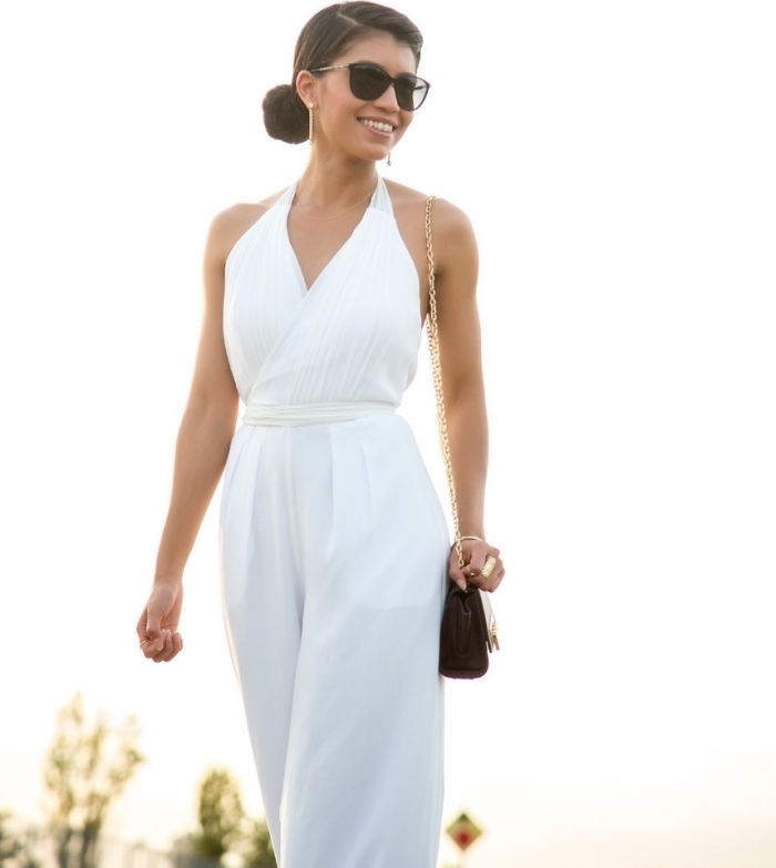 femme élégante en combinaison blanche avec ceinture combinée avec sac à main et paire de lunettes en noir