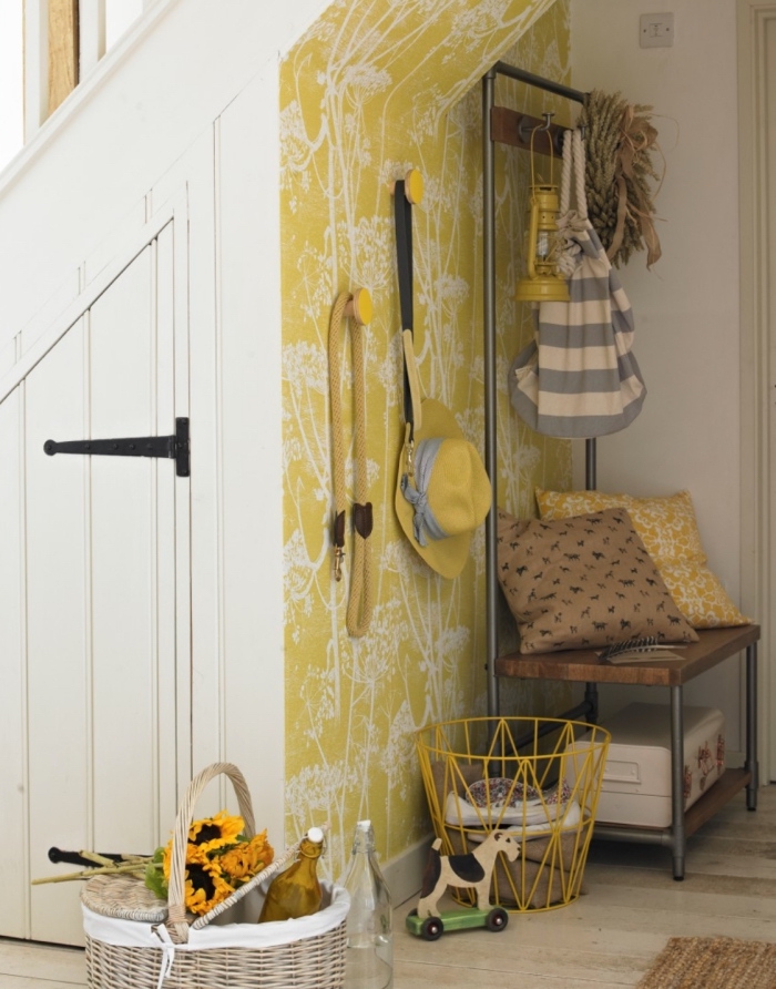 du papier peint à motifs champêtres jaune et blanc qui délimite joliment l'entrée et valorise l'espace sous escalier