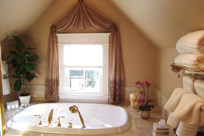 déco cozy dans une salle de bain sous combles aux murs beige avec petite fenêtre, exemple petite baignoire blanche avec robinet doré
