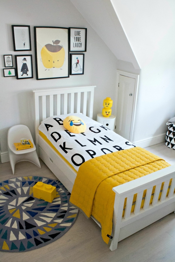 tapis gris, éléments Légo jaunes, chaise blanche, cadres peintures abstraites