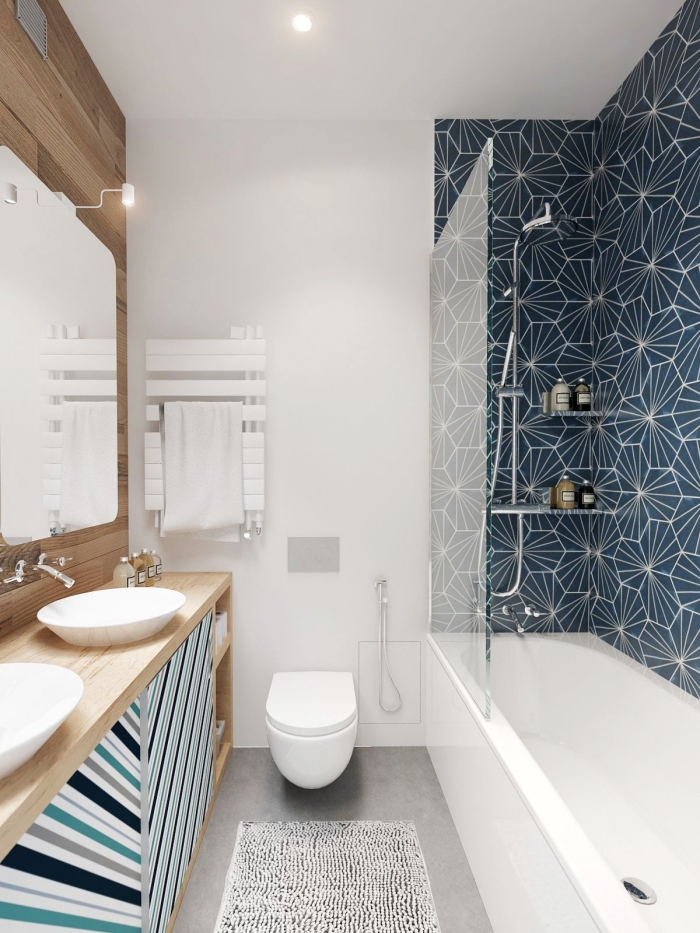 un pan de mur en carrelage carreaux de ciment à motifs graphiques modernes qui permet de délimiter la baignoire dans cette petite salle de bains