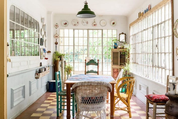 modele de salle à manger dans une maison de campagne avec des chaises vintage dépareillées, sol damier, deco murale vaisselle shabby, table bois avec nappe fleurie