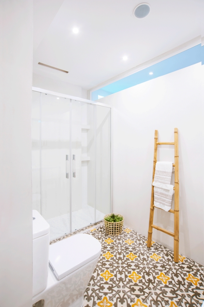 salle de bain monochrome avec douche à l'italienne au sol en carrelage carreaux de ciment à motifs vintage jaune et marron qui réchauffe l'ambiance épurée
