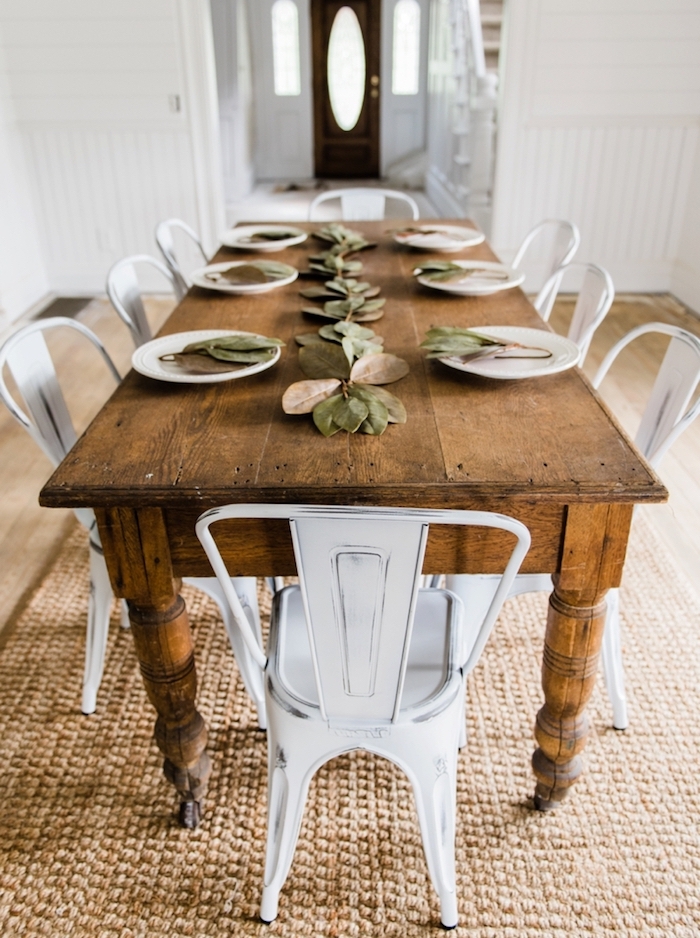 table en bois rustique, chaises metalliques repeintes de peinture blanche, tapis beige, decoration table diner en feuilles séchées
