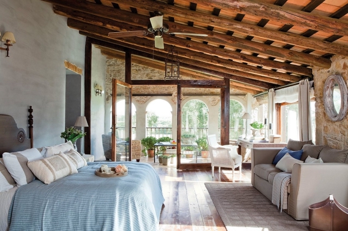 ambiance exotique dans une chambre à coucher au plafond en poutres de bois exposées avec meubles en bois et cuir