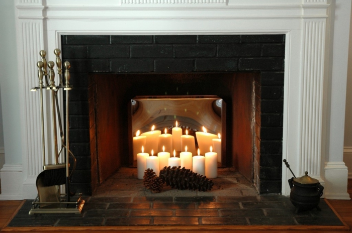 cheminée avec bougies blanches, carreaux noirs, cones et bougies allumées