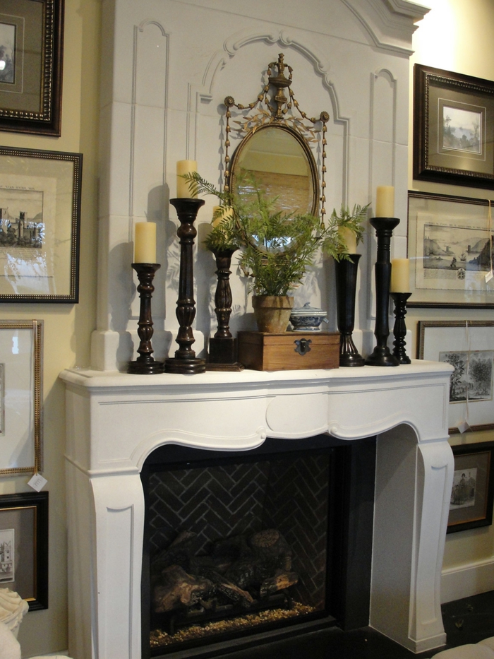 cheminée blanche, bougeoirs anciens noirs, miroir décoratif, cadres peintures 
