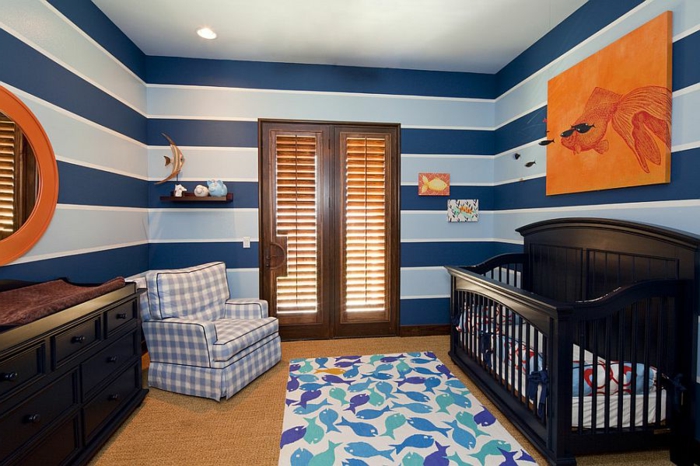 tapis blanc aux motifs poissons, fauteuils carreaux, miroir rond, peinture murale rayures bleues, chambre garcon bebe