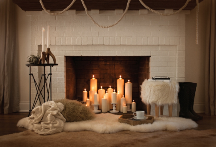 plusieurs bougies allumées, manteau de cheminée en briques blanches, fourrure blanche