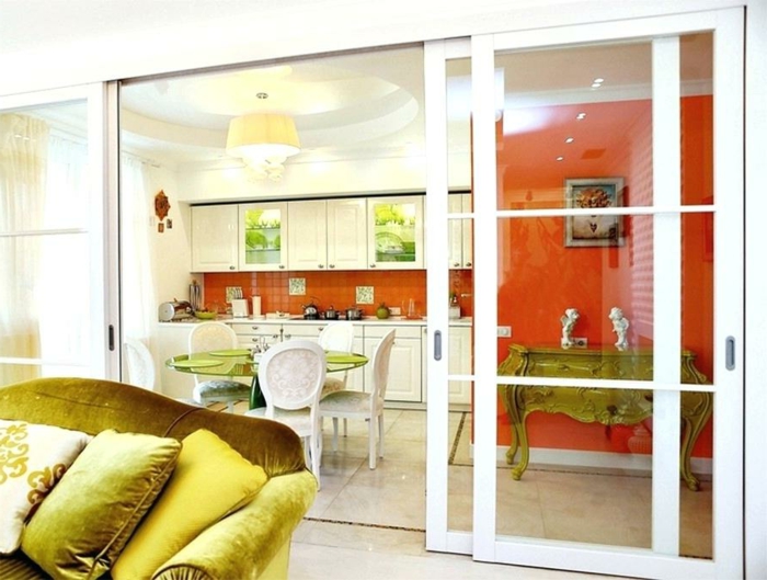 aménagement cuisine avec verriere, console baroque, table ronde verte, chaises médaillon blanches, mur et crédence rouges