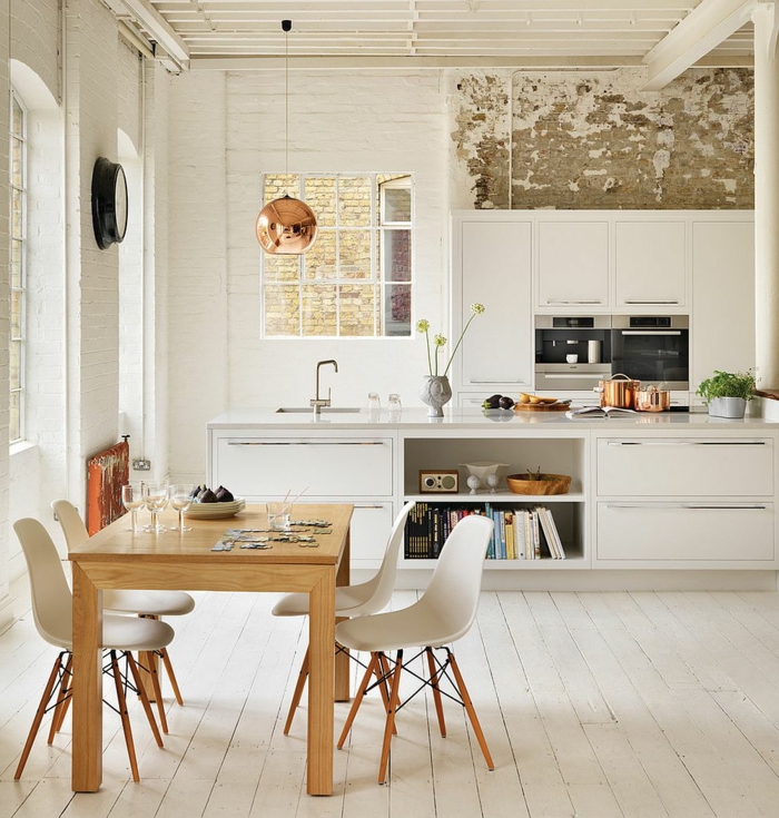 salle à manger et cuisine scandinave, table en bois, chaises scandinaves, lampe cuivrée, ilot de bar blanc, mur blanc au cachet indus