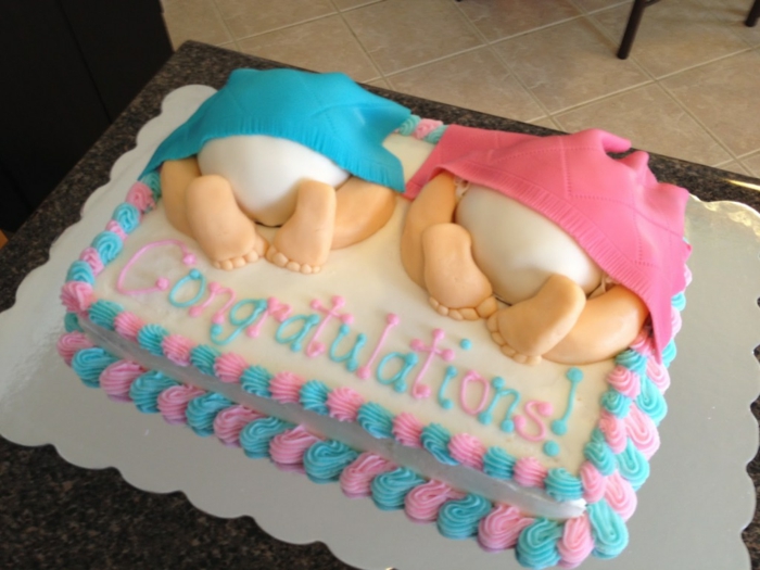 gâteau pour la baby shower de jumeaux, pâte sucrée en rose et bleu pastel, inscription Congratulations, deux bébés qui dorment couverts de couverture en bleu et couverture en rose, cadeau baby shower