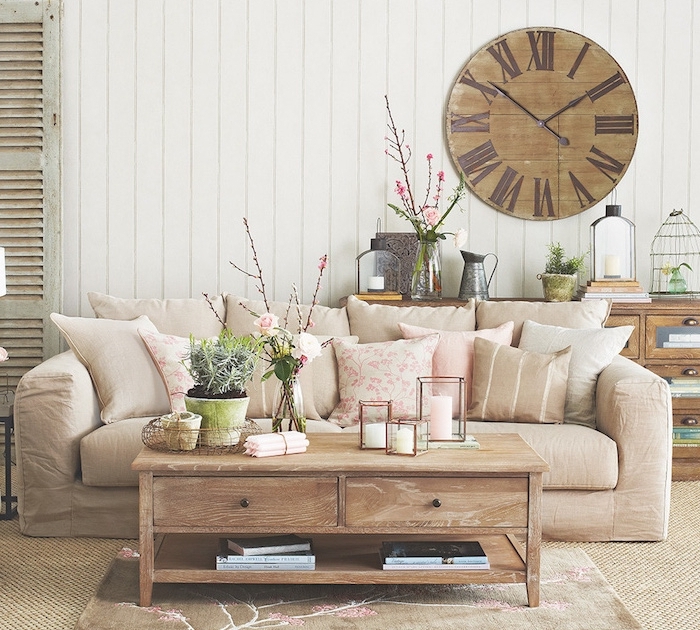 exemple de deco campagne avec canapé beige, table basse bois, lambris blanc, horloge vintage, vases de fleurs, objets anciens