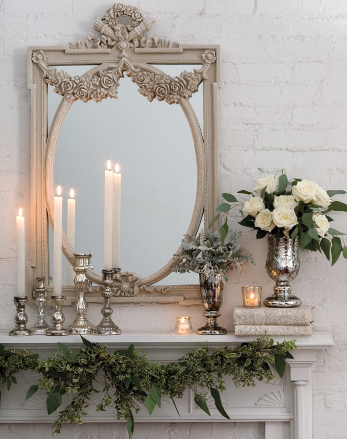 miroir antique, bougies blanches et bougeoirs métalliques, vase argentée avec roses blanches, 