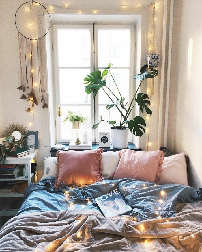joli aménagement chambre, coussins roses, literie grise, pot de fleurs blanc avec plante verte, fenêtre, attrape-rêves, guirlande lumineuse