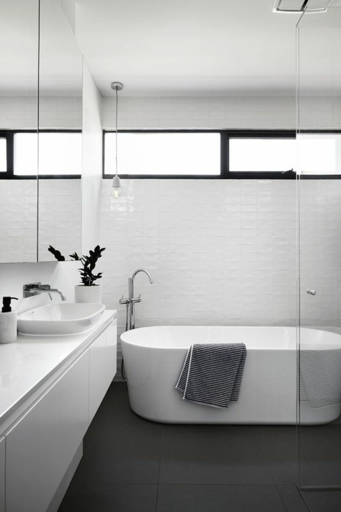 modele de salle de bain, petite salle de bain avec baignoire blanche ovale, sol carrelage noir, meuble suspendu blanc, carrelage mural blanc aux motifs briques