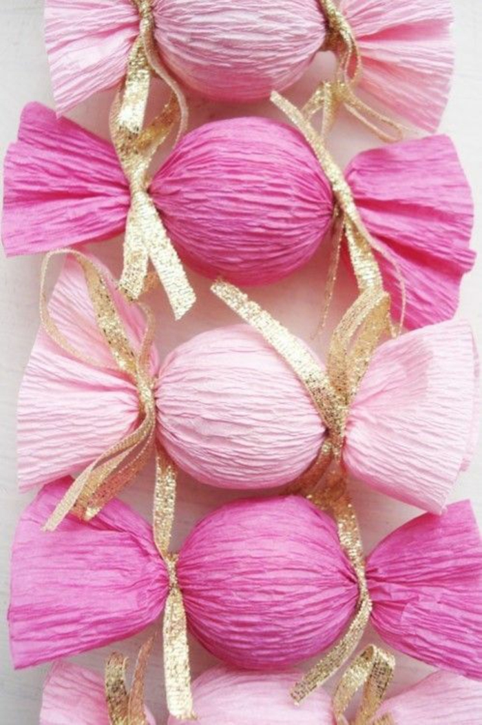 sucreries enveloppées en papier cadeaux couleur rose pale et fuchsia, avec deux nœuds en fil doré qui nouent les deux extrémités, baby shower fille