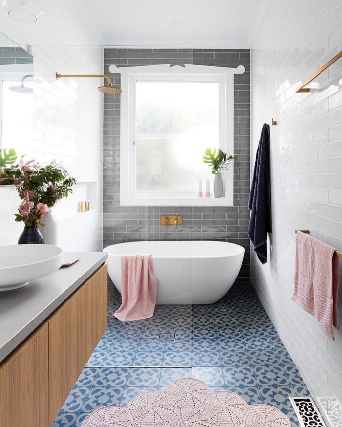 le carrelage aspect carreaux de ciment à motifs marguerites bleues de cette salle de bains moderne est associé avec des carreaux de métro blancs et gris