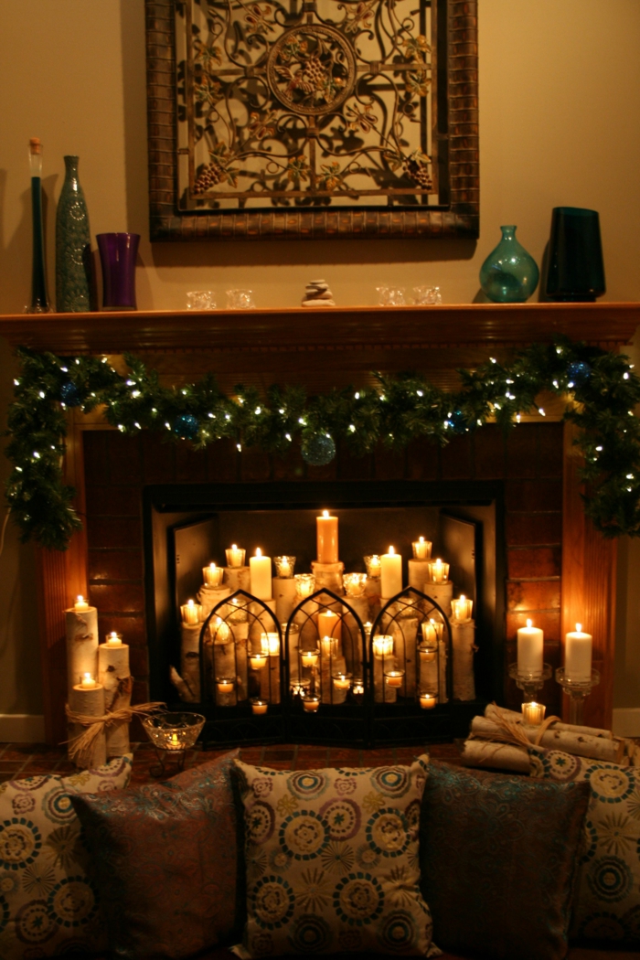fausse cheminée décorative, plusieurs bougies allumées, lampes lumineuses et coussins déco