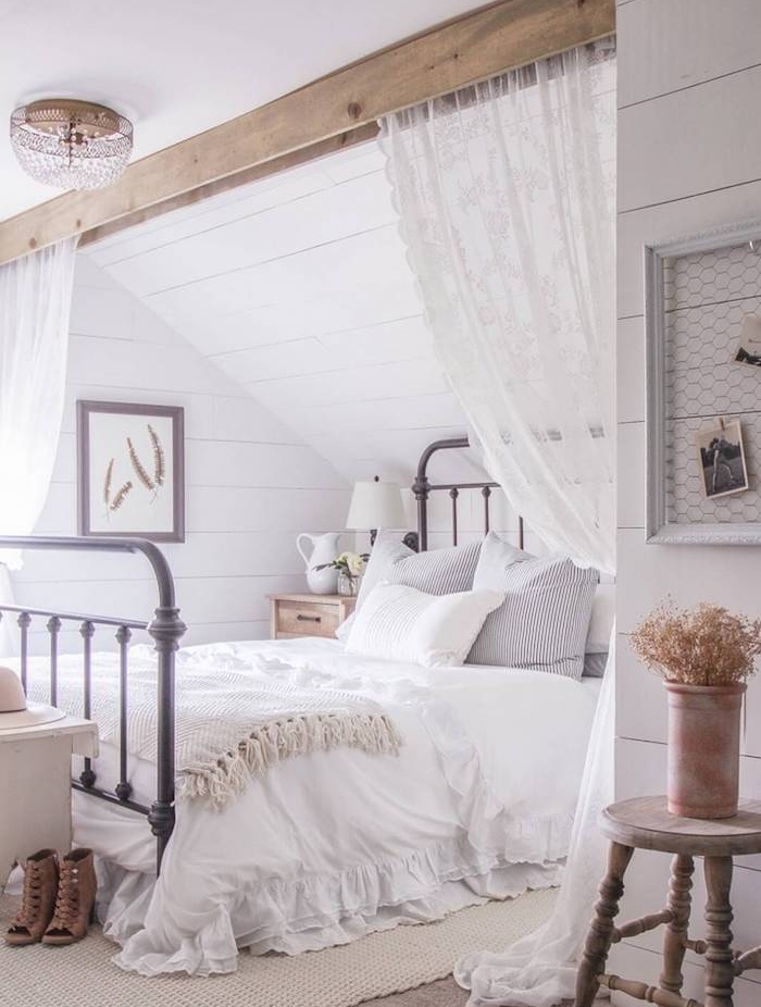 deco chambre sous pente avec poutre bois apparente, lit metallique vintage, linge de lit blanc, tapis beige, rideaux dentelle