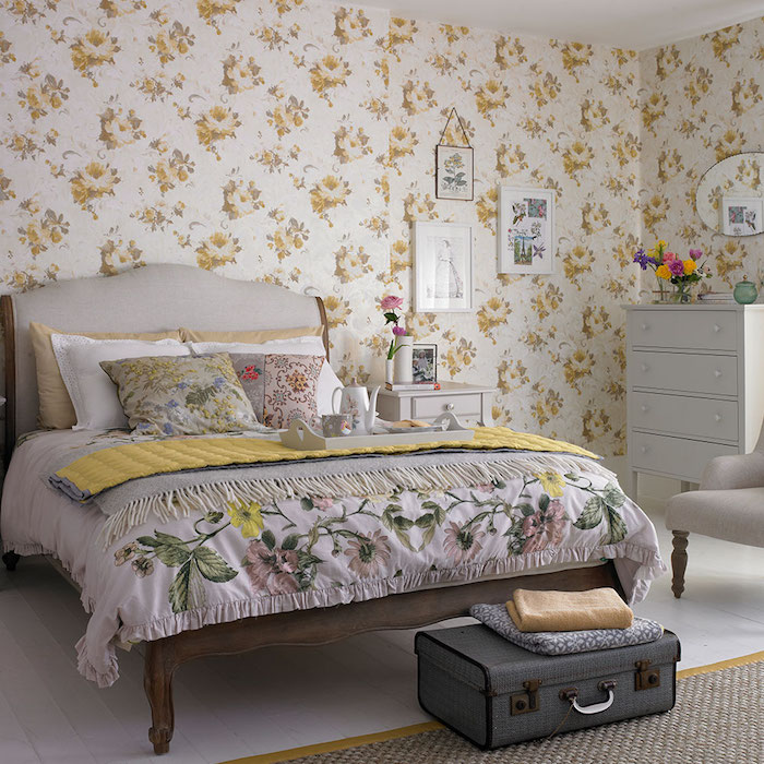papier peint fleuri dans une chambre deco shabby, linge de lit fleuri, commode gris clair, bout de lit en malle vintage grise, parquet blanchi