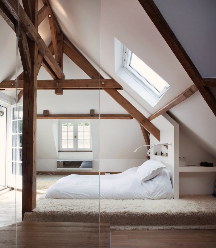 modèle de chambre à coucher aménagée dans l'esprit scandinave aux murs blancs avec charpente apparente de bois foncé