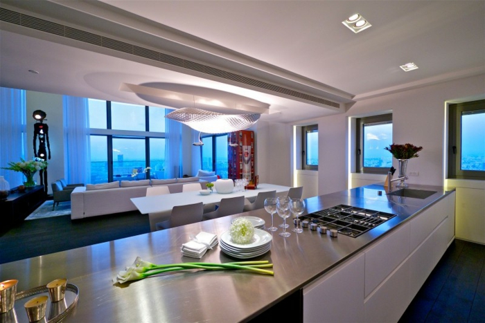separation cuisine salon avec un grand comptoir, plafond gris clair, salon avec mur vitrée et vue, grande table blanche, décor contemporain