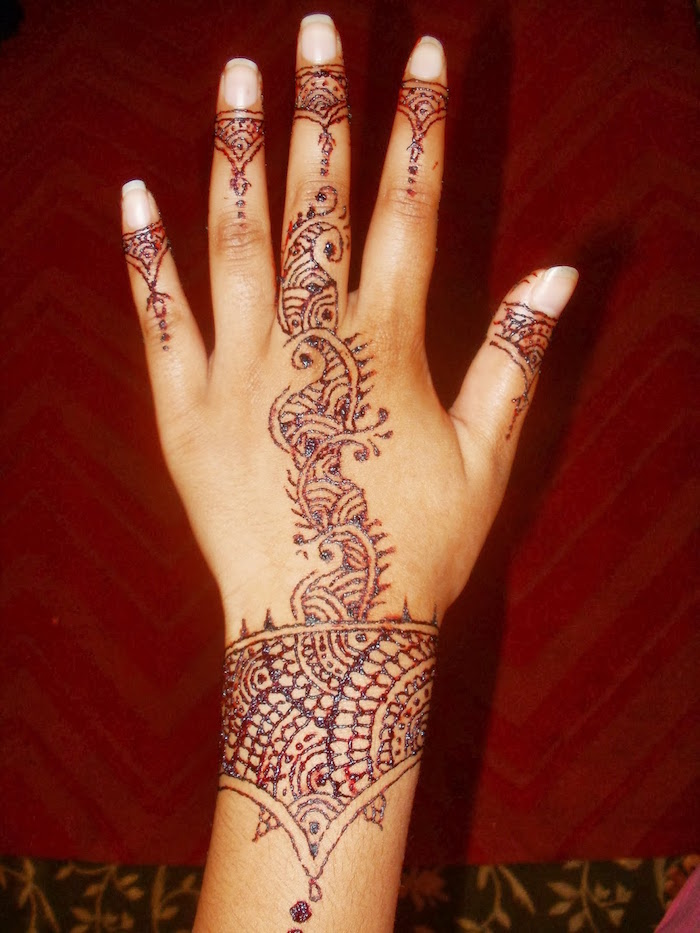 dessin au henné couleur marron cuivre sur la main et le poignet 