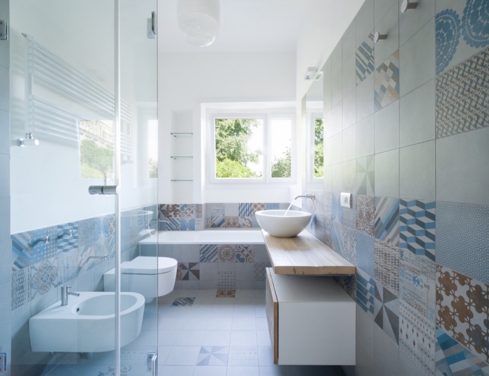 des carreaux de ciment patchwork en tons doux qui recouvrent les murs et le sol de cette salle de bains pleine de douceur et de luminosité