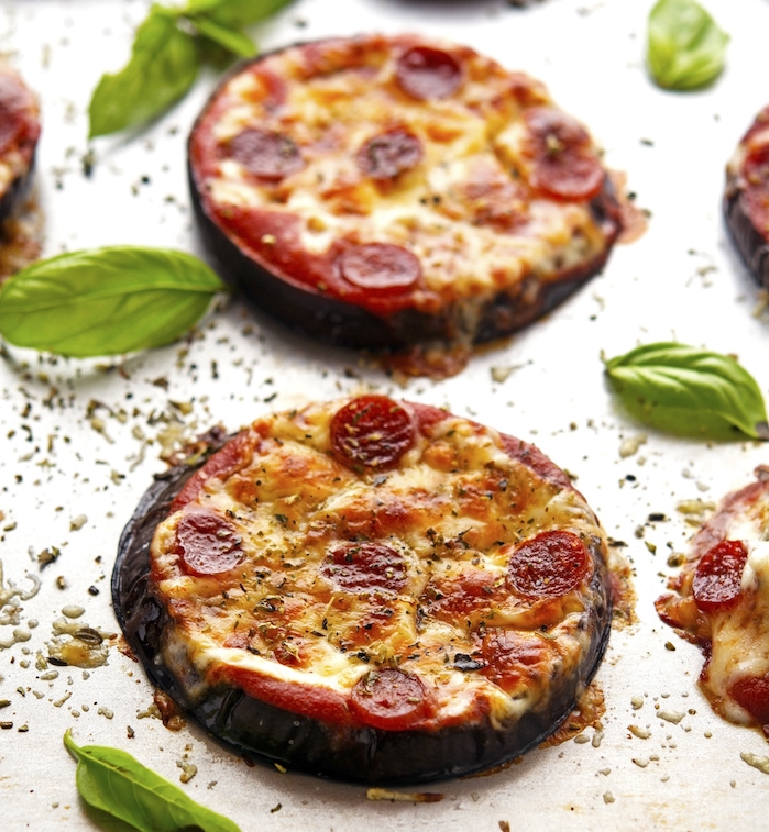idée de mini pizza avec une base d aubergine rôti au four, avec du fromage et saucisson et sur une sauce marinara