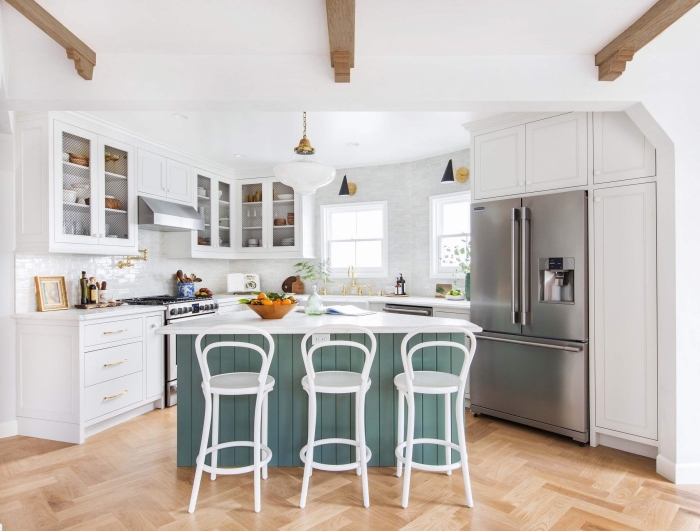 ambiance conviviale et authentique dans une cuisine avec des poutres de bois apparentes au plafond et un ilot de cuisine à façade en lambris peint bleu gris 