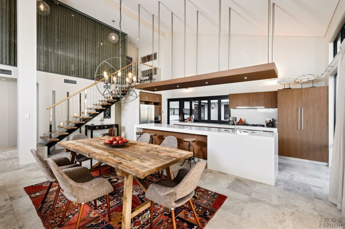 separation cuisine salon avec grand comptoir blanc, tapis patchwork style ethnique, table en bois brut, escalier loft