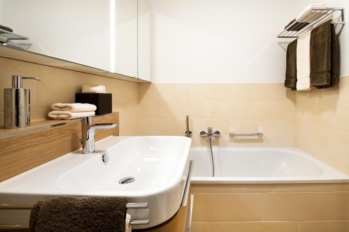 quelles couleurs pour une petite salle de bain claire, modèle de petite baignoire intégrée dans une salle de bain au carrelage beige
