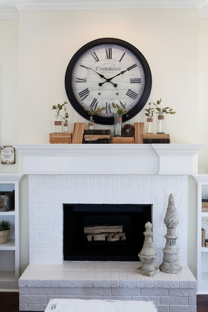 foyer décoratif blanc, horloge style shabby et vieux livres sur une cheminée blanche décorative