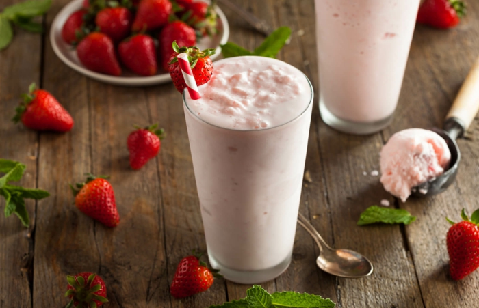 milkshake à la glace vanille rose, fraises, feuilles de menthe, meuble en bois brut, cuillère de glace