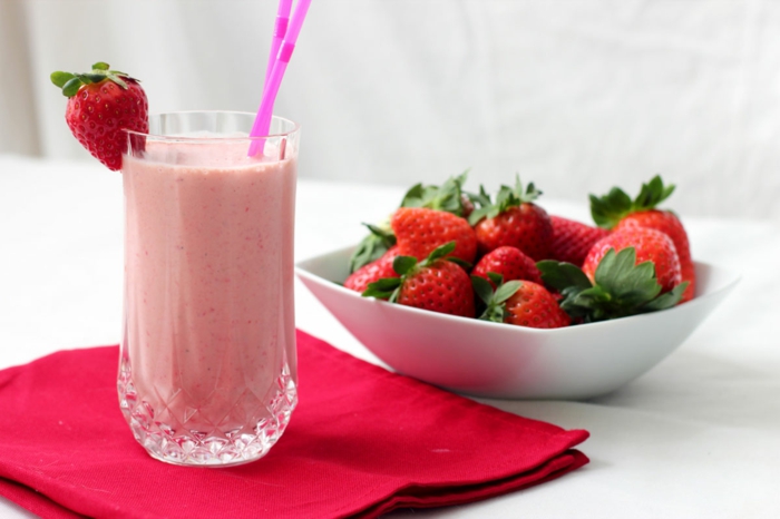 assiette blanche pleine de fraises, serviette rouge, tasse de milkshake aux fraises classique