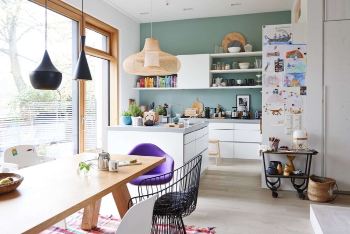 petite cuisine avec ilot central compact en blanc et gris qui sépare visuellement la cuisine et le séjour, un mur vert pour délimiter l'espace cuisine ouverte sur le salon