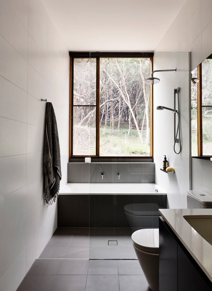 modele de salle de bain espace limité aux murs blancs avec plancher en carrelage gris foncé, modèle petite baignoire